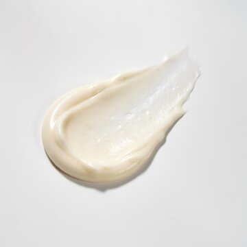 A smooth smear of white cosmetic cream or moisturizer on a neutral background with skin care beauty product face cream smooth texture topical cream
