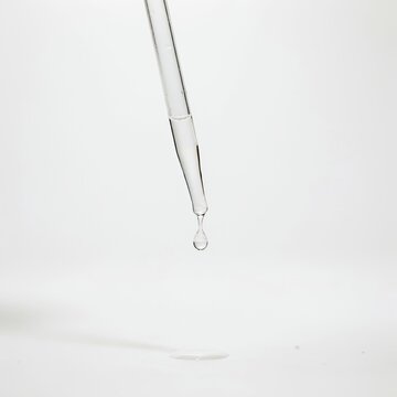 Clear liquid serum drop falling from a glass pipette with skincare product beauty product cosmetic serum transparent liquid skin treatment cosmetic ingredi