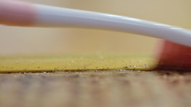 Closeup cleaning detail. Steady hand removes particles from fabric and threshold junction. Close up of toothbrush delicately brushing boundary between carpet and door frame
