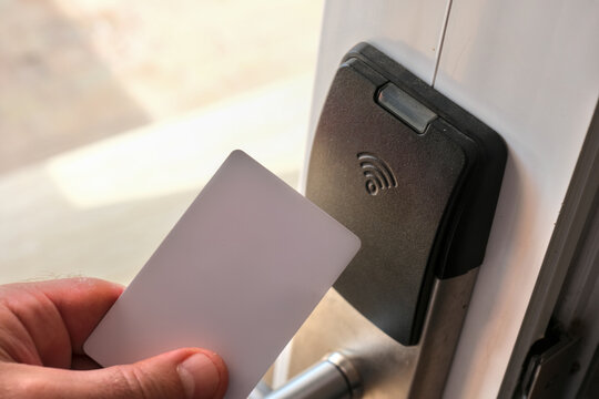 Hand holding a contactless key card near a smart door lock, illustrating secure access control and modern keyless entry technology.