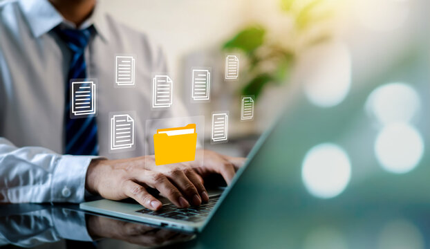 Businessman typing on laptop with virtual folder icon and document files on screen. Concept of digital data management, file organization, electronic archive, and document workflow.