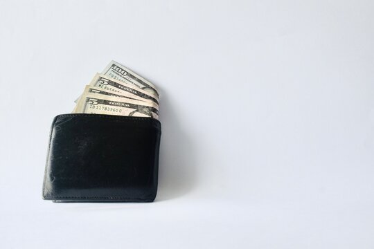 Black leather wallet with visible US dollar bills isolated on a clean white background.