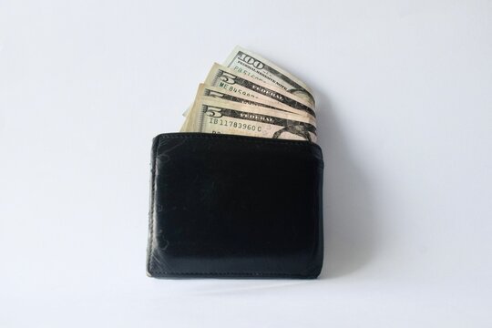 Black leather wallet with visible US dollar bills isolated on a clean white background.