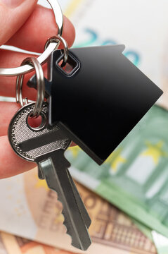 Hand holding house keys over euro currency