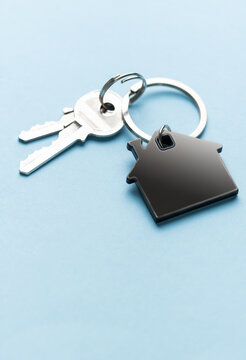 House keys with home shape keychain on blue background