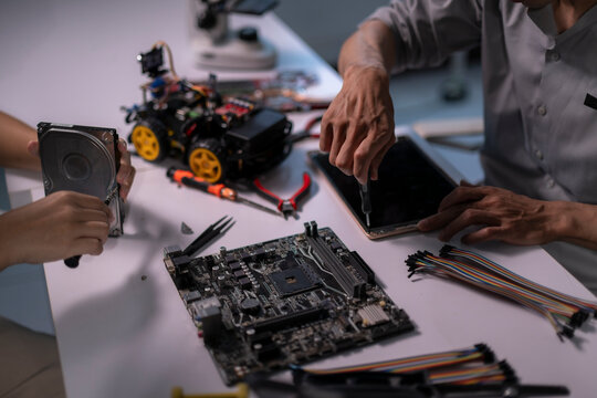 People constructing electronics and robotics components at workbench