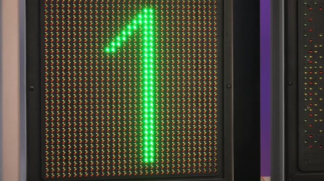 Digital display shows green number one. Orange arrow points upward and right. Red digit nine on pixel screen