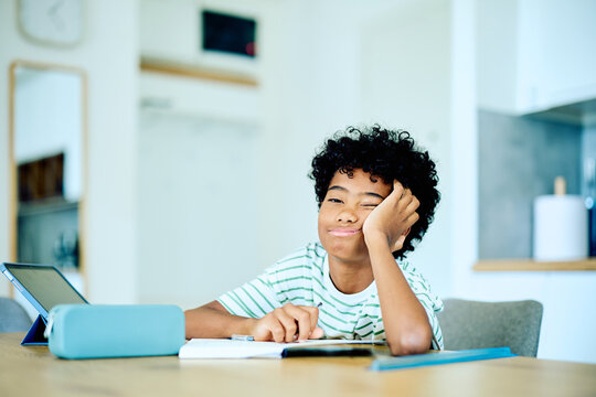Little student boy feeling unmotivated and tired while studying at home, leaning on his hand. Procrastination and education concept