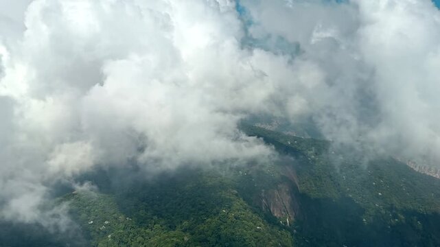 White clouds drift above tropical hills during a Rio helicopter flight, Aerial footage reveals brief city views through changing coastal weather