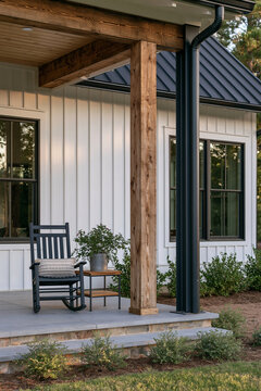 Modern barn home porch with wooden beam, black steel column, rocking chair, and small table