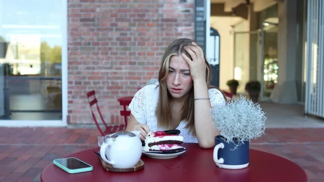 Worried woman checks her empty wallet at an outdoor cafe after enjoying cake and tea realizing she has no money left to pay the bill and feeling stressed about the situation