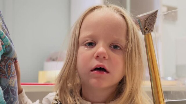 Cute blonde toddler girl playing indoors, shouting with mouth wide open, making funny angry faces