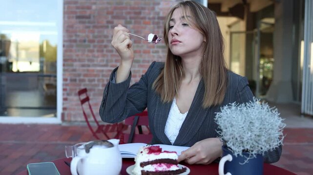 Picky cafe customer carefully examines a slice of berry cake before tasting it while remaining visibly dissatisfied with the dessert quality and presentation at her table