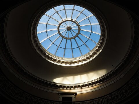 A large, round dome skylight with multi-pane glass panels framed in a classic rotunda design