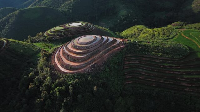 Drone aerial over terraced hills and a wide green valley in T&agrave; X&ugrave;a, Vietnam.