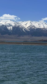 Beautiful scenic view of Sayram Lake with turquoise water and snow-capped Tianshan mountains in Xinjiang, China.