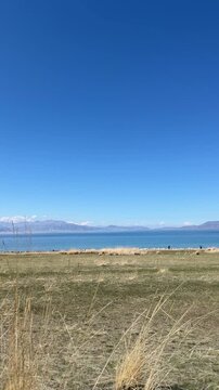 Beautiful scenic view of Sayram Lake with turquoise water and snow-capped Tianshan mountains in Xinjiang, China.