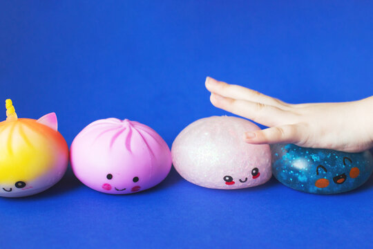 Child hand playing with colorful squishy stress toys