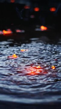 Glowing orange sparks falling and splashing into dark rippling water