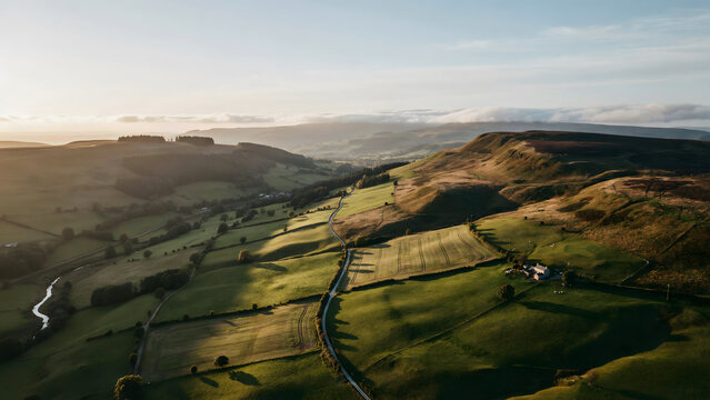 Aerial view of a lush green valley with rolling hills and agricultural fields at sunrise with soft golden light and long shadows across land