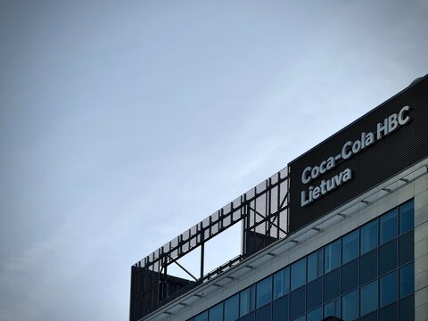 Low-angle photo of the "Coca-Cola HBC Lietuva" corporate logo on a modern office facade in Vilnius, Lithuania. Ideal for stock photo needs related to the beverage industry, FMCG corporations