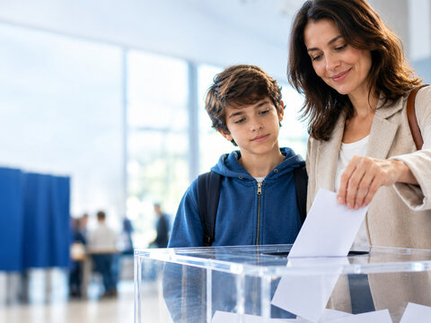 Madre votando junto a su hijo en un colegio electoral, concepto de educaci&oacute;n democr&aacute;tica y participaci&oacute;n ciudadana para el 15 de septiembre, D&iacute;a Internacional de la Democracia