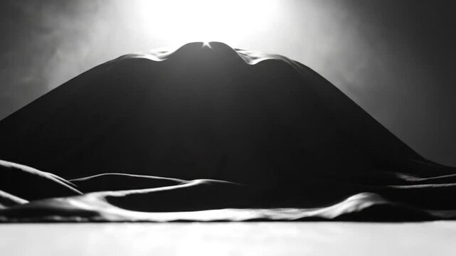 Mysterious unveiling of an object covered in dark fabric, cinematic studio lighting creating dramatic shadows and anticipation