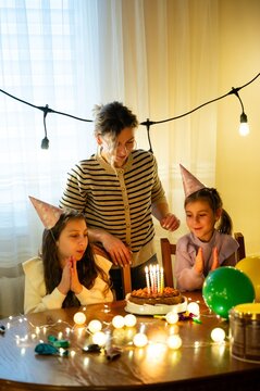 Celebrating a joyful birthday gathering with kids around a decorated table and a delicious cake, as lights twinkle in the background creating a magical atmosphere