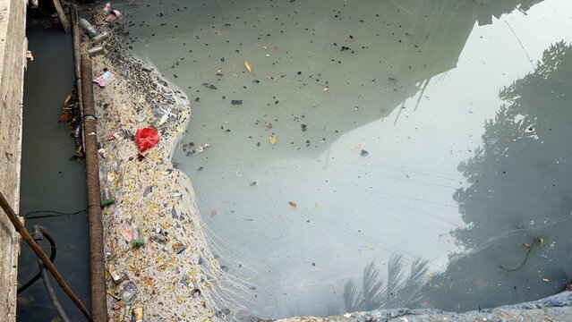 Polluted dirty gray color stagnant river water with urban litter