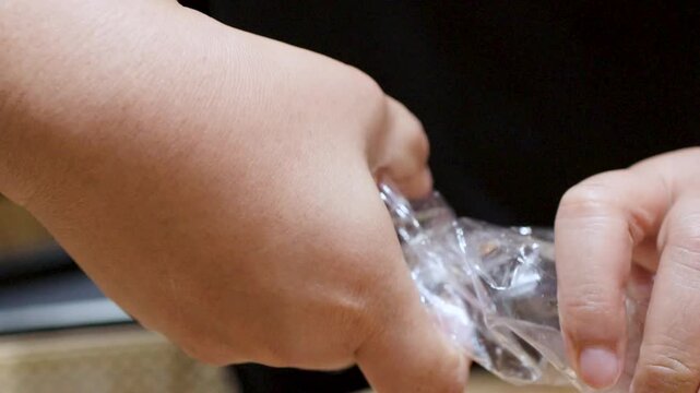 Hands Crushing and Twisting Empty Plastic Bottle for Recycling