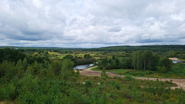 Expansive natural landscape with winding river and dense green forests under cloudy sky