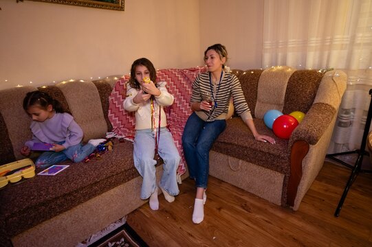 Joyful family gathering in a cozy living room with children playing and adults enjoying snacks during a lively indoor celebration in the evening