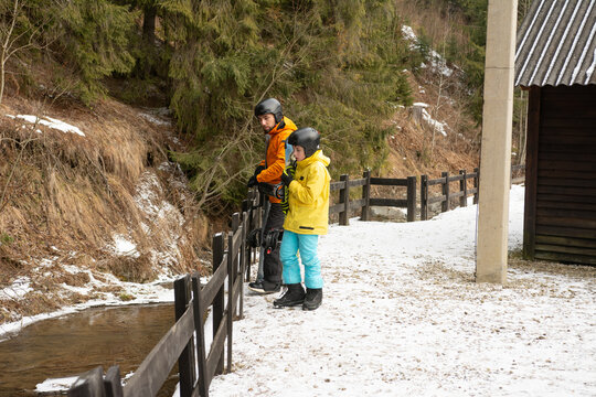 Enjoying a winter day by the stream in the snowy forest with family, capturing moments of joy and adventure together in the great outdoors