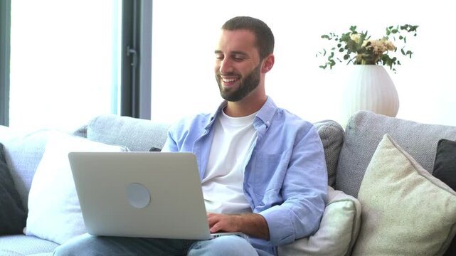 Frustrated man scratching his head while working on a laptop computer, displaying stress and concern as he encounters problems and difficulties during his remote work session from home