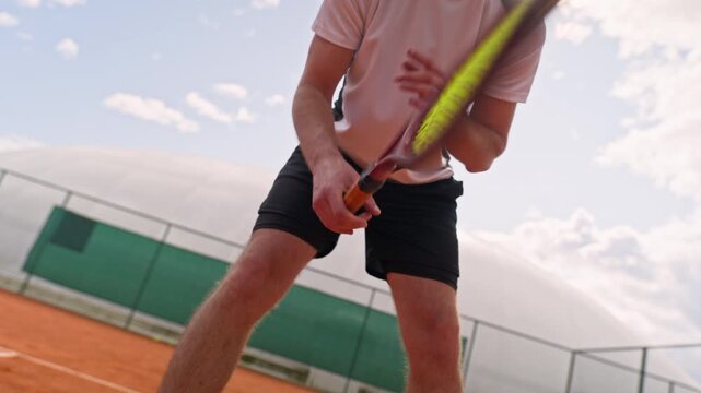 Caucasian young adult man preparing to receive serve with racket on clay court in slow motion. Footage suitable for tennis training apps, athletic gear advertising and sports fitness promos