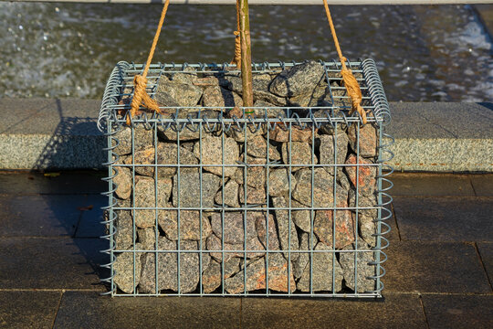 Gabion Plant Stand with a small growing tree. Stones in a metal wire block. Modern urban landscaping design