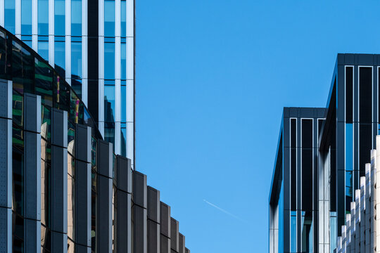Office architecture and facades frame blue sky in the City of London where geometric buildings create a vertical pattern across the cityscape