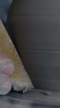 Slow motion close-up of pot made of clay spinning on pottery wheel and male hand shaping artwork with tool. Ceramics and art studio concept.