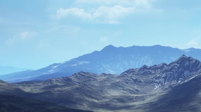 A wide view of mountains in a valley. The scene shows rocky peaks and flat areas under bright sunlight. The sky is clear with a few clouds present.