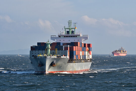 Container ship sailing through rough seas with stacked shipping containers