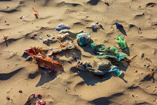 Plastic pollution on the beach. Plastic bag trash washed up on the sandy shore