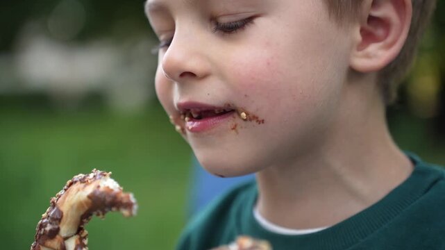 Little boy enjoying a pretzel in a city park, capturing a simple childhood snack and relaxed outdoor leisure moment.
