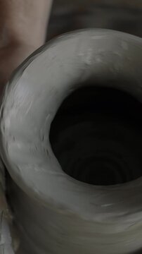 Top view of ceramic pot rotating on wheel and dirty hands shaping earthenware in workshop. Traditional craft and creative people concept.