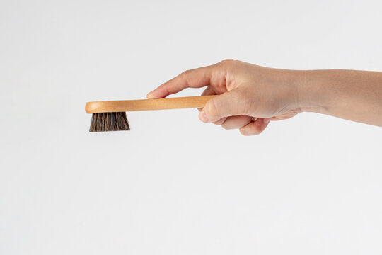 Wooden-handled bag polishing brush held in hand against a white background.