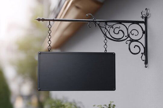 Blank black sign hanging on decorative bracket outside store