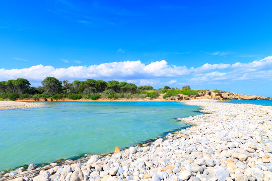 Idyllic tropical lagoon with turquoise waters and a pebble shore under a bright blue sky