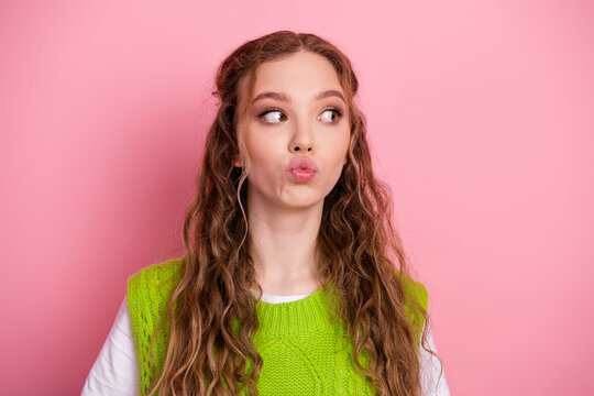Young female student on pink background wearing a bright vest smiles and puckers lips creating a playful fashion lifestyle image