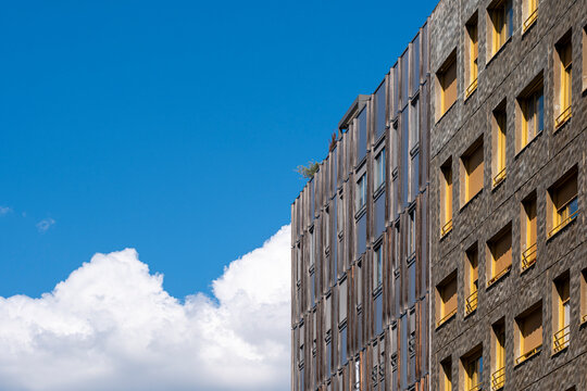 Apartment building beside blue sky and clouds creates a residential composition with copy space in La Confluence Lyon where the facade rises into the frame