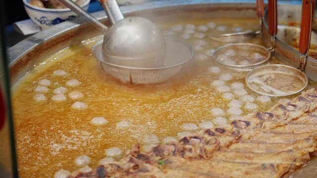 At a Guizhou beef noodle shop, a large pot of hot broth is poured over the beef, steaming is rising