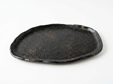 Handmade rustic black ceramic plate with textured surface and irregular organic shape isolated on white background